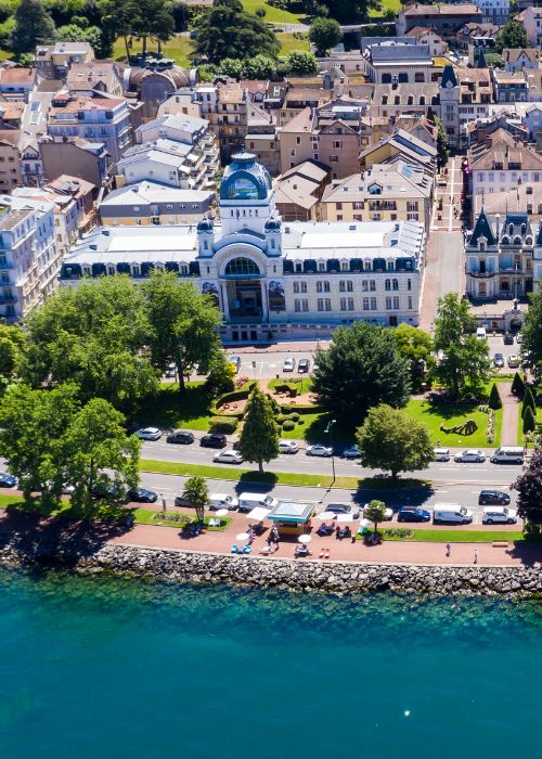 Vue aérienne au bord du lac Léman, entouré d'arbres et de voitures garées.